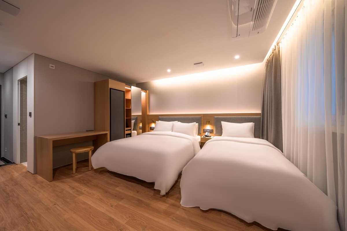 Una habitación de hotel moderna con dos camas, un escritorio y un tocador.