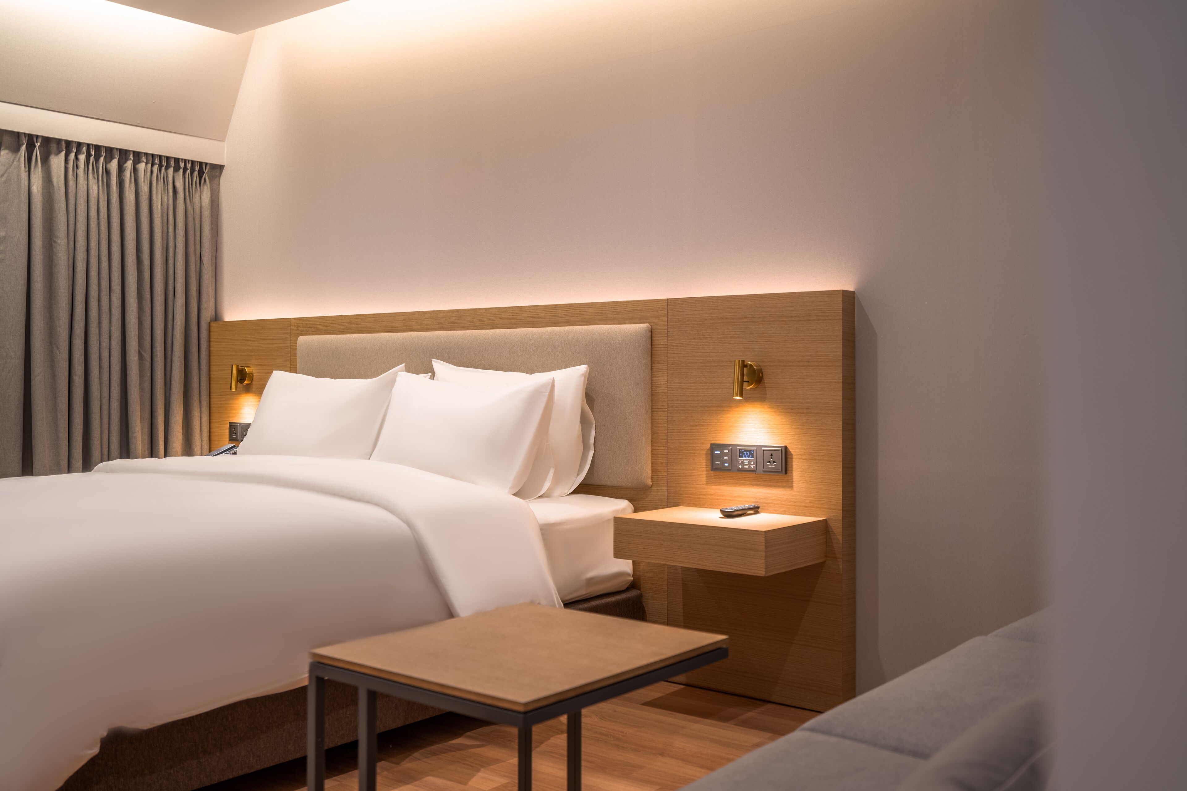 A modern hotel room with a large bed, bedside tables, and a small table.