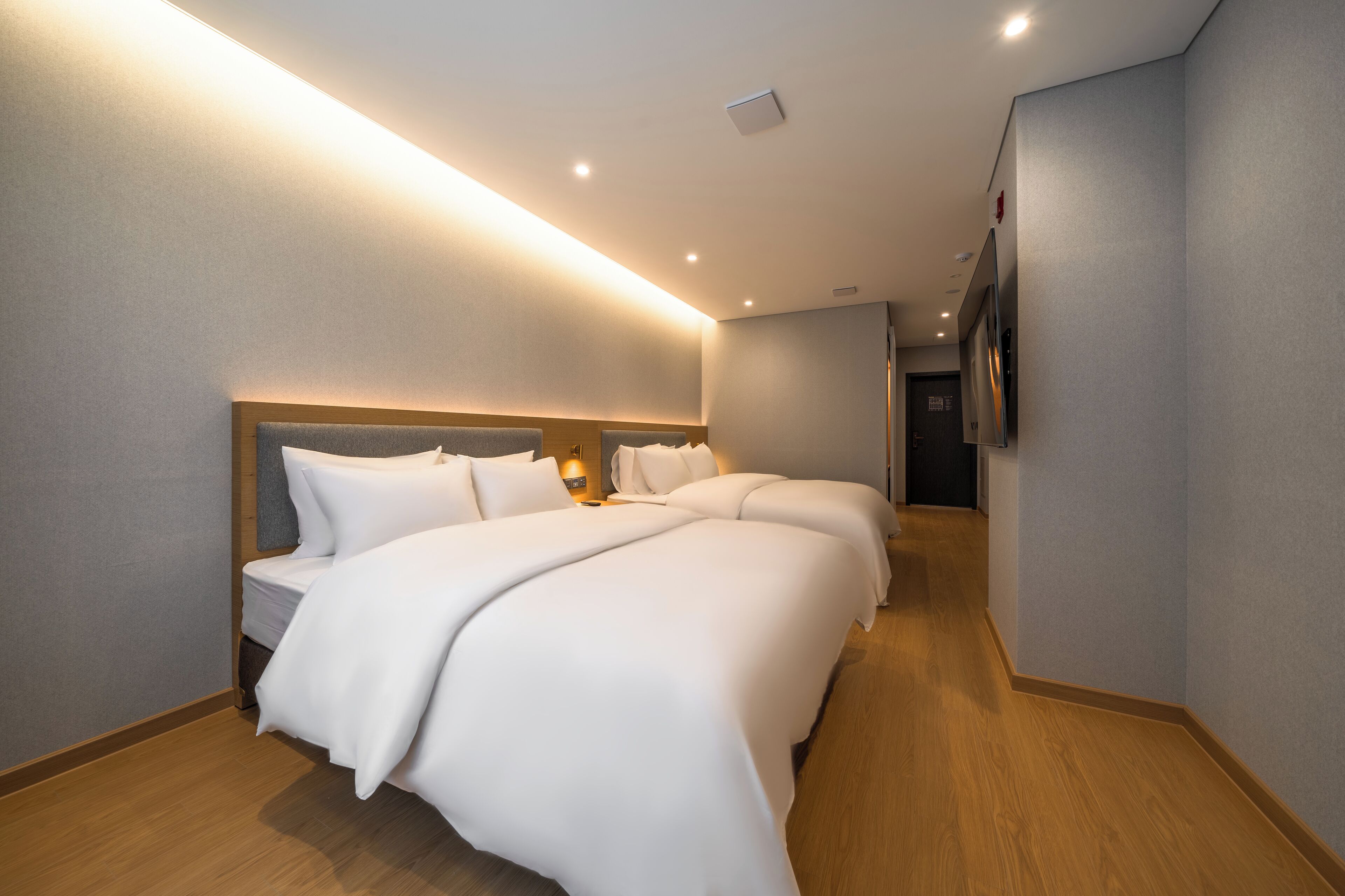 A hotel room with a large bed, bedside tables, and a flat-screen TV mounted on the wall.