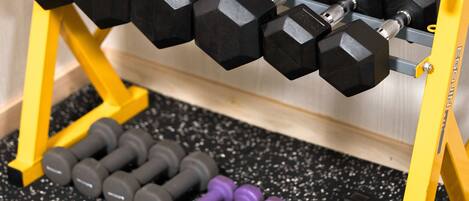 A set of dumbbells on a rack with a speckled floor.