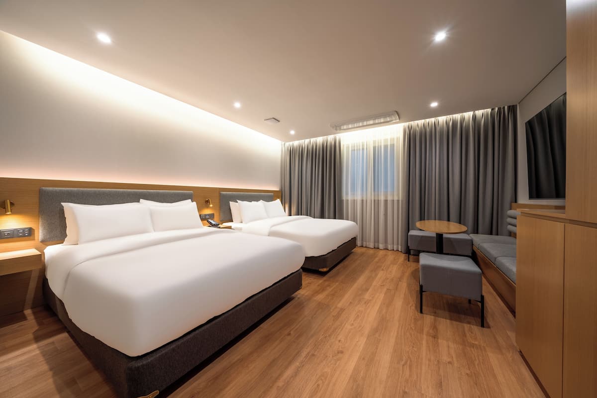 Una habitación de hotel moderna con dos camas, una zona de estar y un televisor.