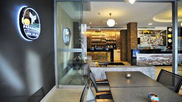 A modern interior with a coffee bar, seating area, and a view of a cityscape.