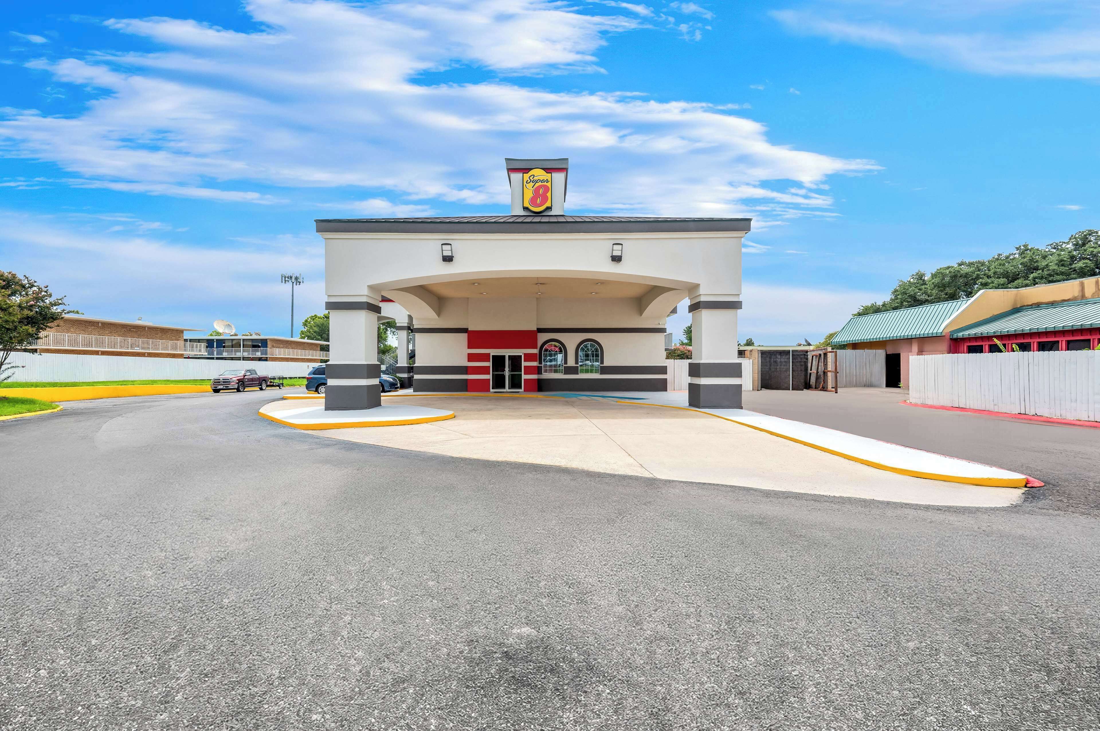 A gas station with a prominent 'Super 8' sign, a large parking lot, and a clear blue sky.