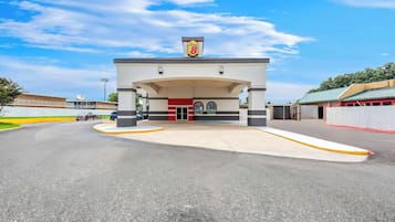 A gas station with a prominent 'Super 8' sign, a large parking lot, and a clear blue sky.