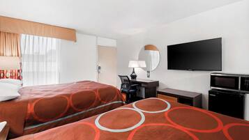 Habitación de hotel con dos camas, un escritorio con silla, televisor de pantalla plana, microondas y un refrigerador pequeño.