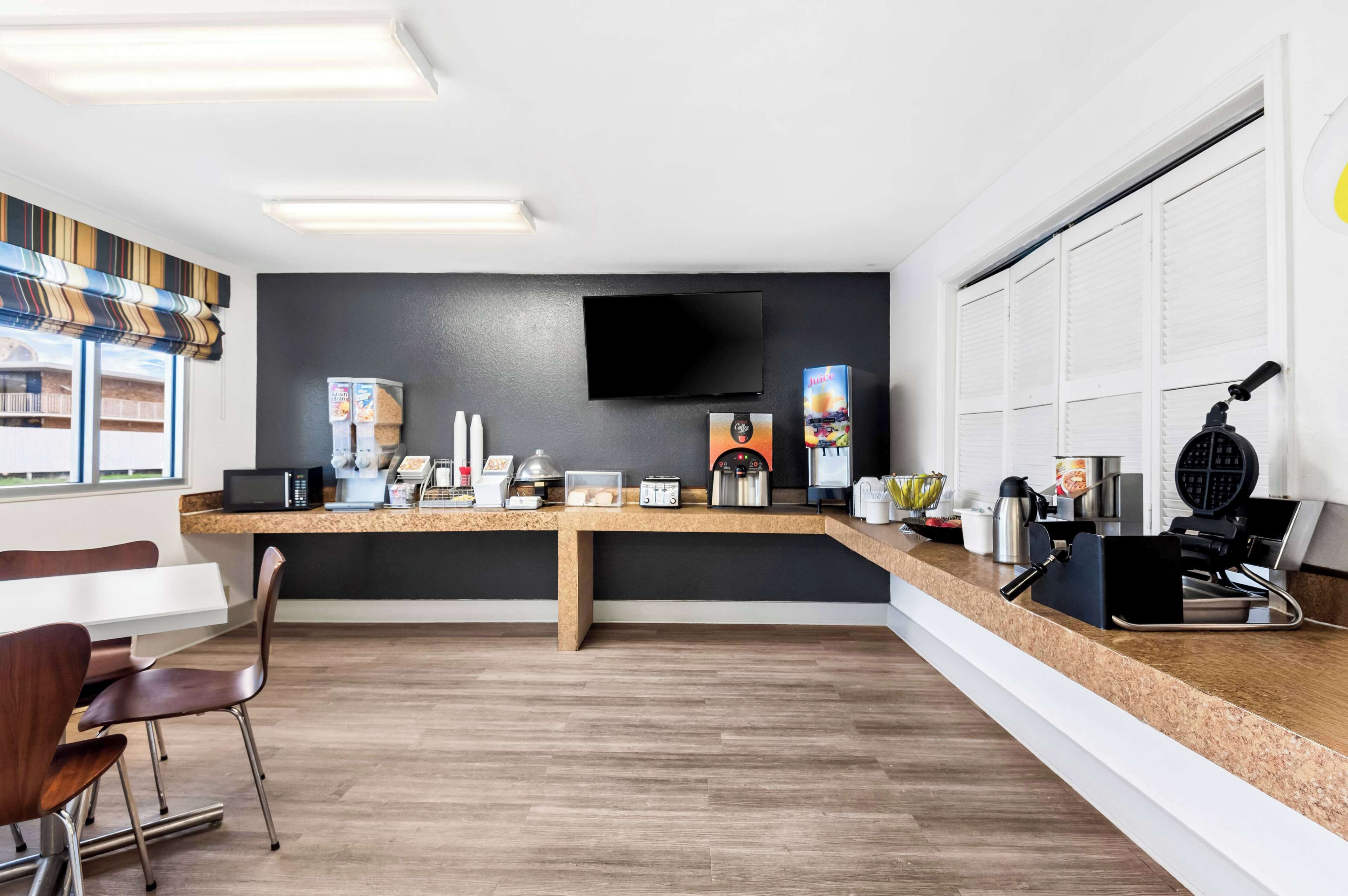Een moderne keuken met een flatscreen televisie, magnetron, broodrooster en een wafelijzer.