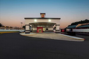 Una estación de servicio con un llamativo letrero de '7-Eleven', un acceso cubierto y un cielo despejado.