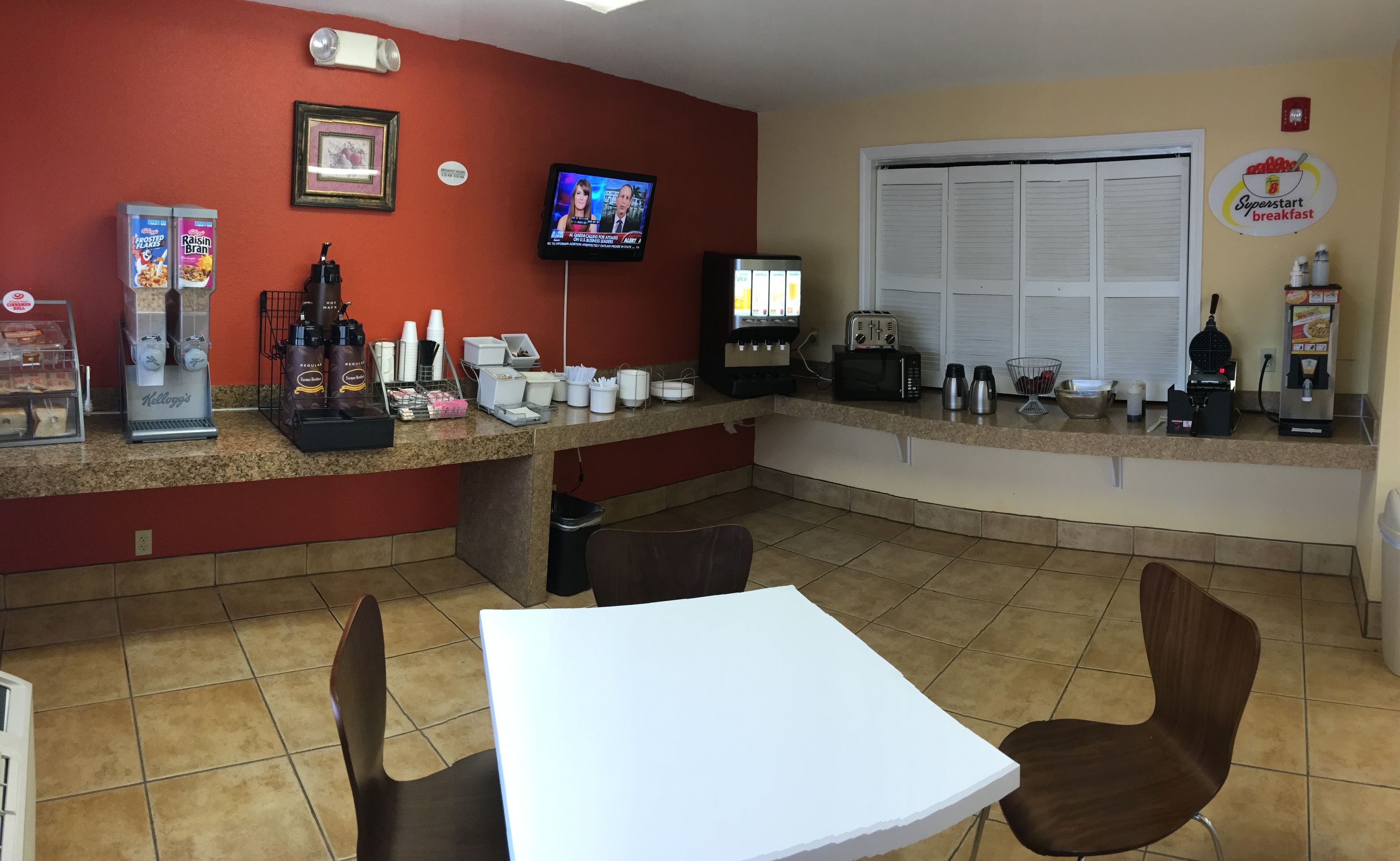 A breakfast area with a counter, coffee machines, and a TV.