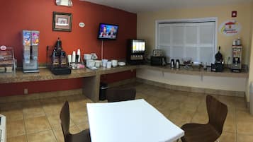 A breakfast area with a counter, coffee machines, and a TV.
