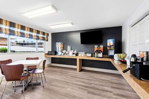 Una cocina moderna con comedor, que cuenta con un amplio ventanal, un televisor de pantalla plana y diversos electrodomésticos.