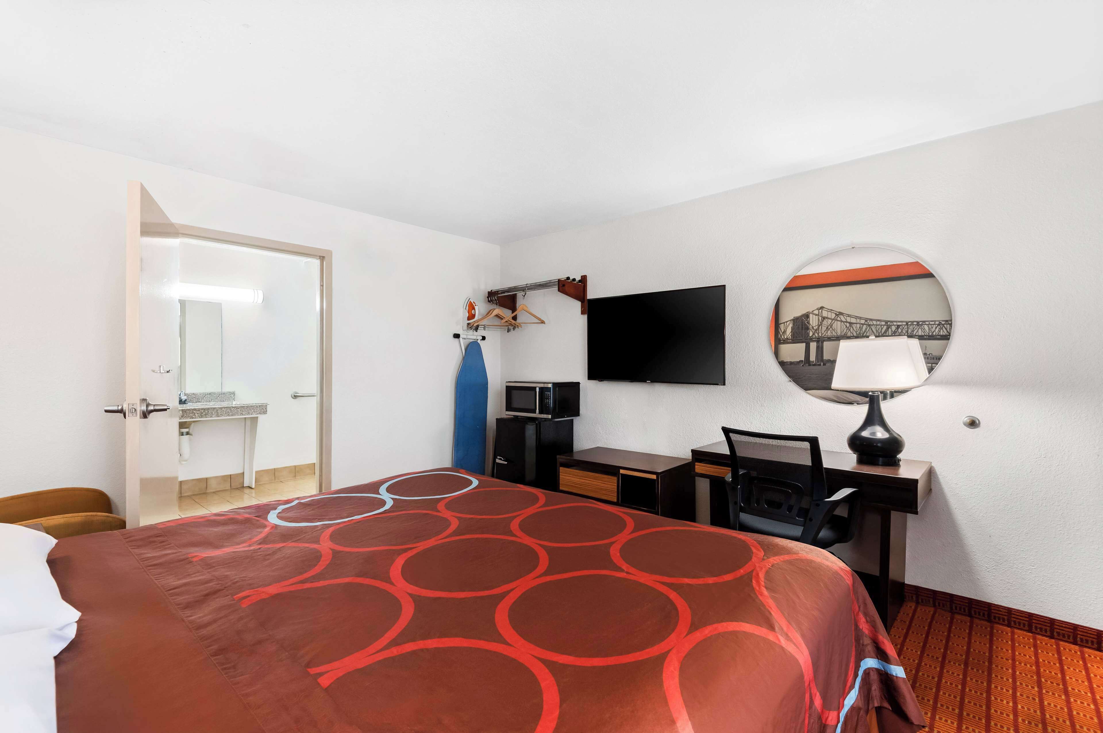 A hotel room with a bed, desk, chair, TV, and a mirror.