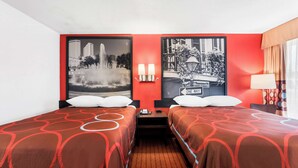 A hotel room with two beds, a nightstand with a phone, and two wall-mounted lamps.