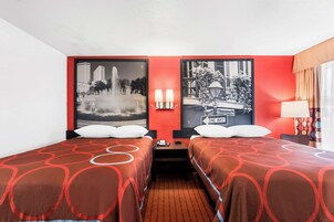 Habitación de hotel con dos camas, una mesita de noche con teléfono y dos lámparas de pared.