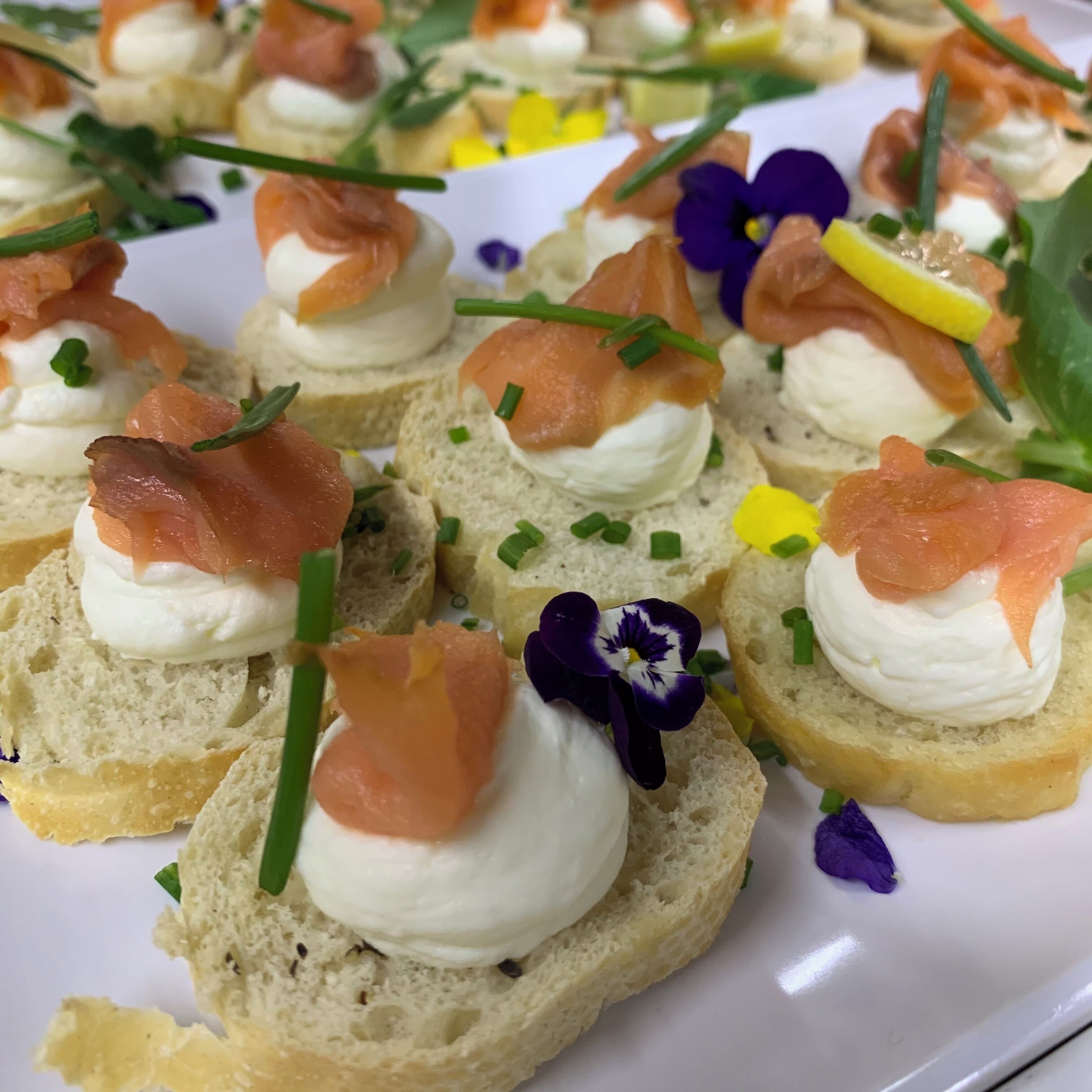 A plate of appetizers with smoked salmon, cream cheese, and garnishes.