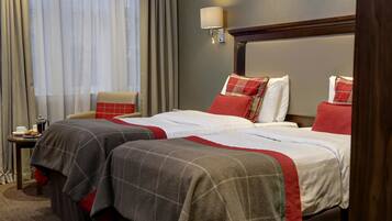 Une chambre d’hôtel avec deux lits, une table de chevet, une lampe et une fenêtre avec des rideaux.