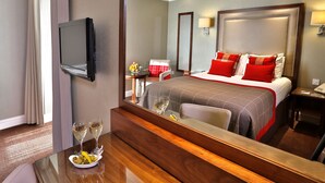 A hotel room with a large bed, a bedside table with a bowl of fruit and glasses, a TV mounted on the wall, and a mirror reflecting the room. - Best Western Motherwell Centre Moorings Hotel (Motherwell)