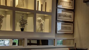 A restaurant with a seating area featuring cushioned booths and tables, a patterned floor, and wall-mounted shelves with framed artwork and decorative items. - Best Western Motherwell Centre Moorings Hotel (Motherwell)