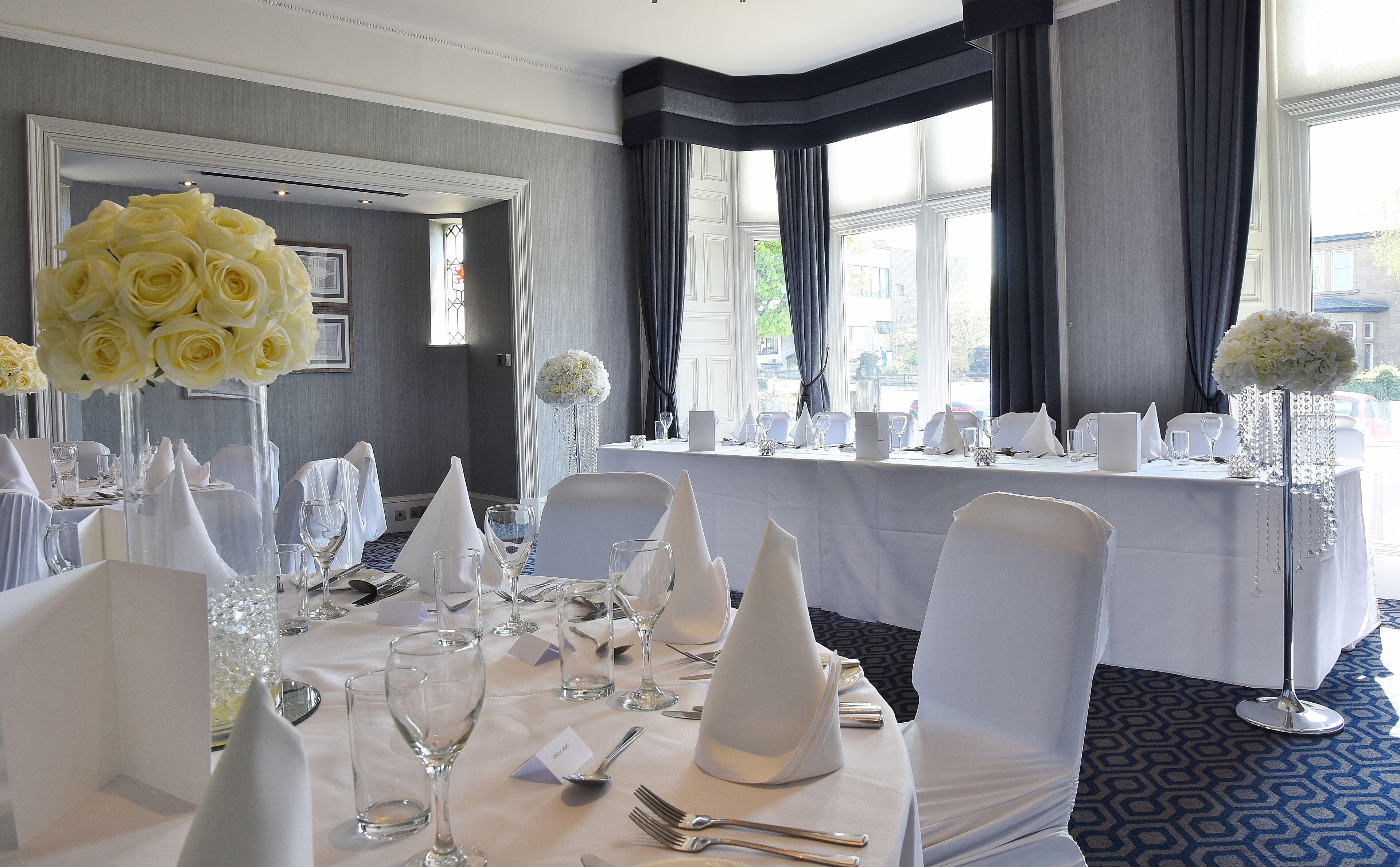 Ein Hotelrestaurant mit runden Tischen, weißen Tischdecken und Stühlen.