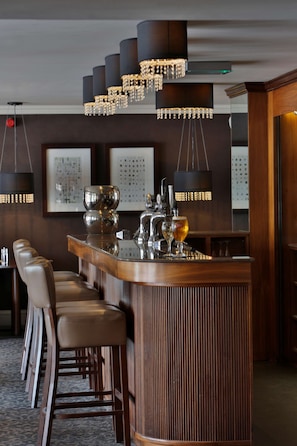 A bar area with a wooden bar counter, multiple bar stools, and hanging pendant lights. - Best Western Motherwell Centre Moorings Hotel (Motherwell)