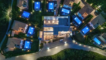 Vista aérea de una zona residencial con varias casas, cada una con piscina y zonas de estar al aire libre.