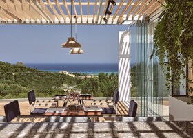 Una terraza con mesa lista para comer, con vista a un paisaje costero.