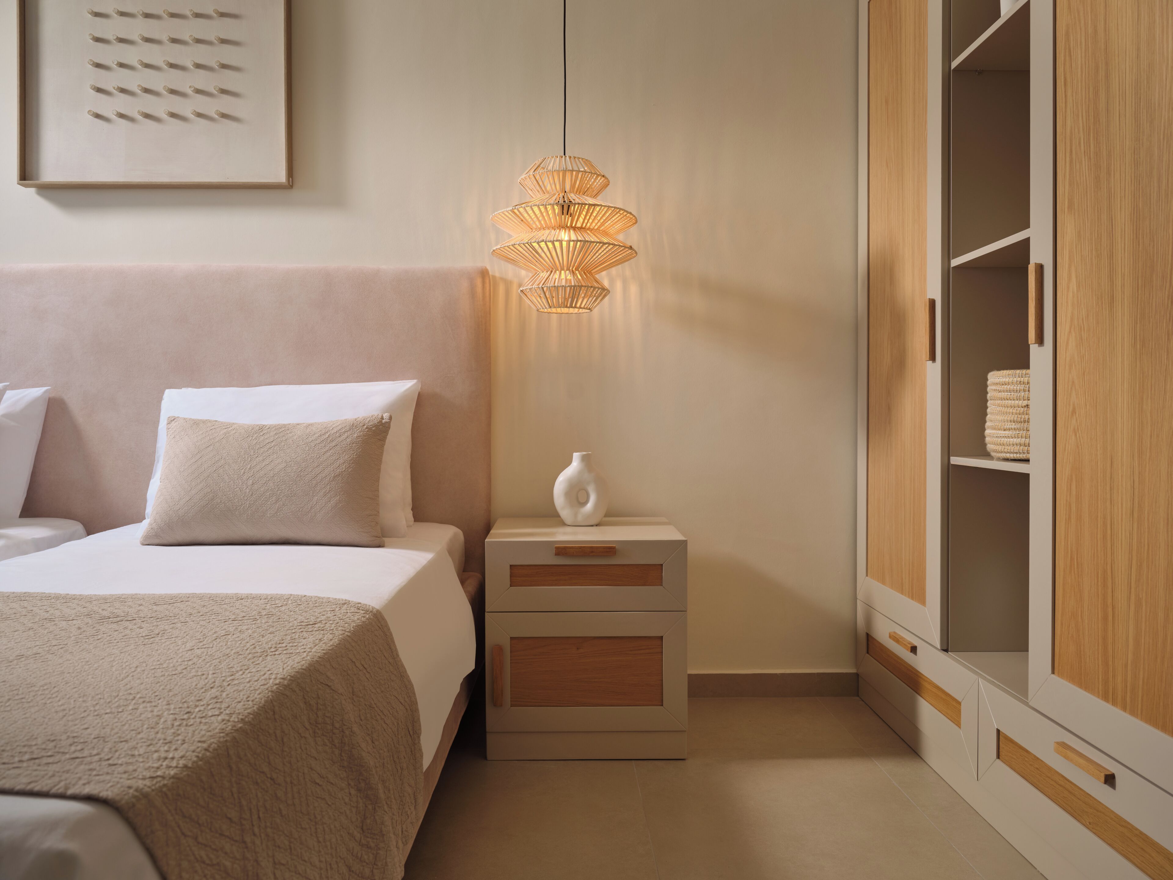 A bedroom with a bed, bedside table, nightstand, and wardrobe.