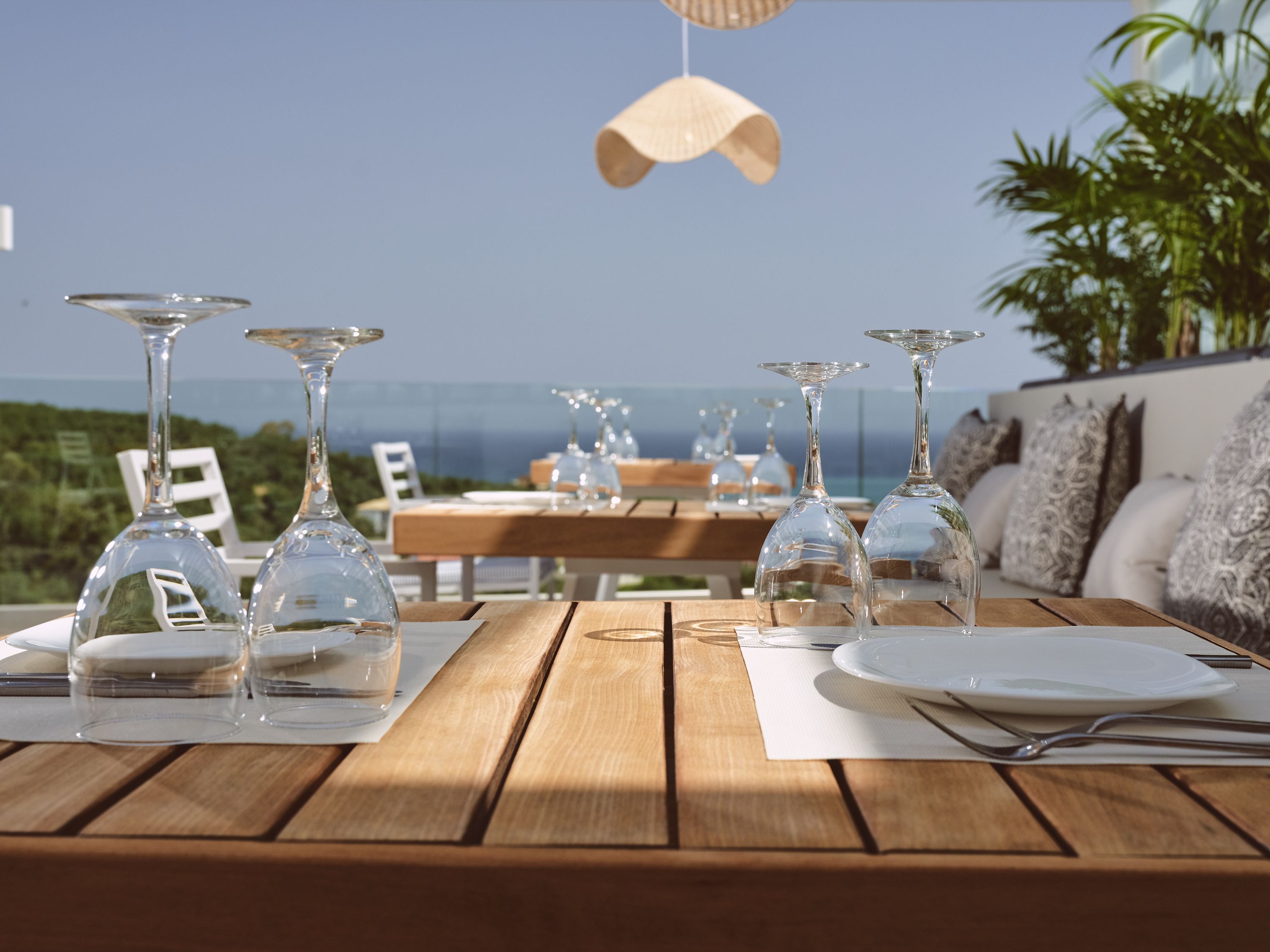 A dining table with wine glasses and plates, overlooking a scenic view.