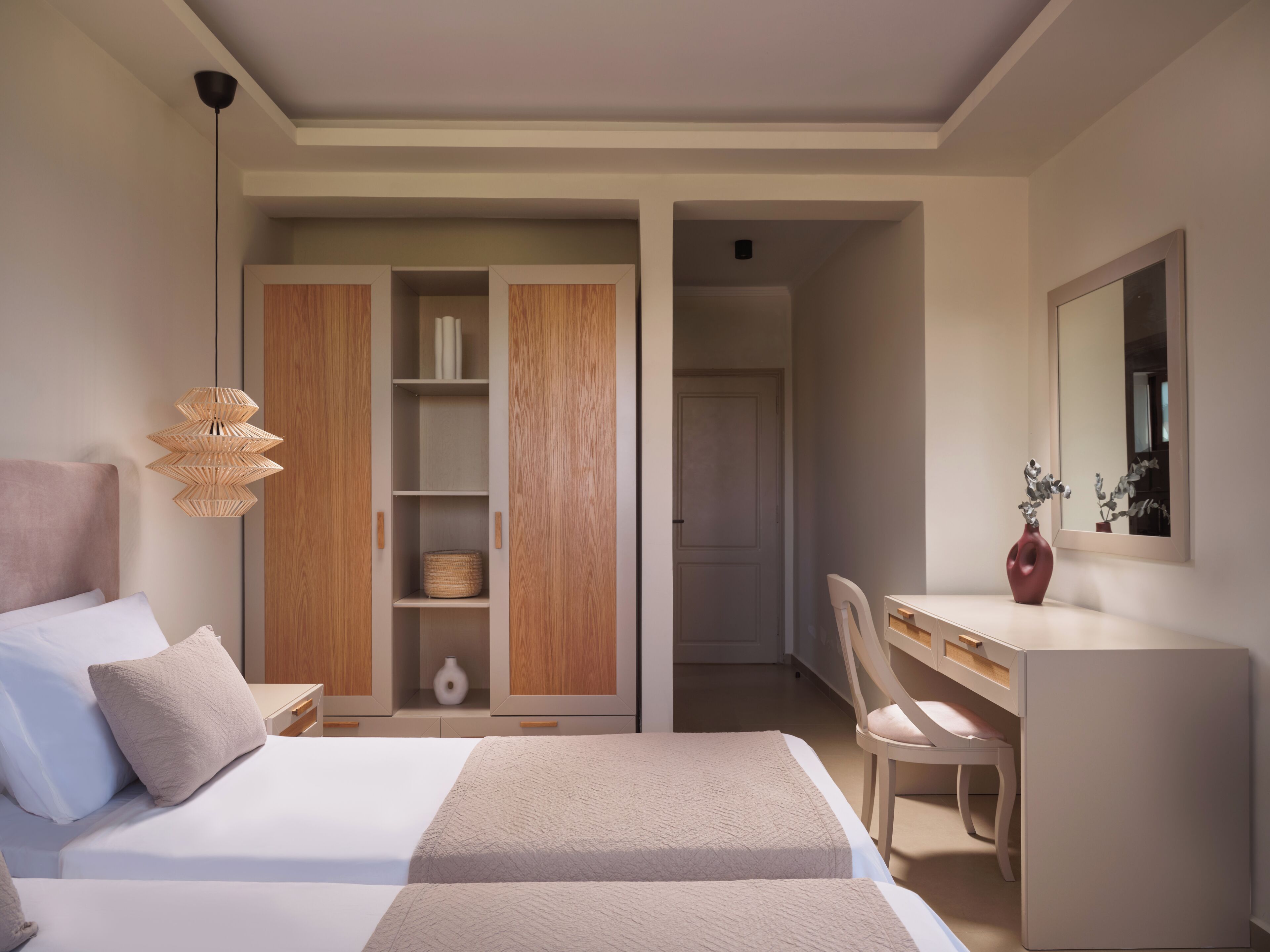 A bedroom with two beds, a wardrobe, a desk, and a chair.