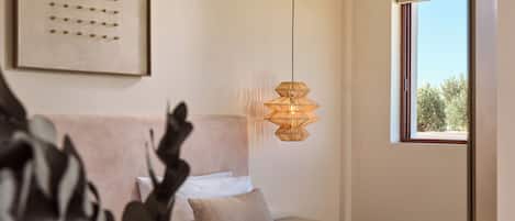 Ett modernt sovrum med en säng, ett sängbord och en hängande lampa.