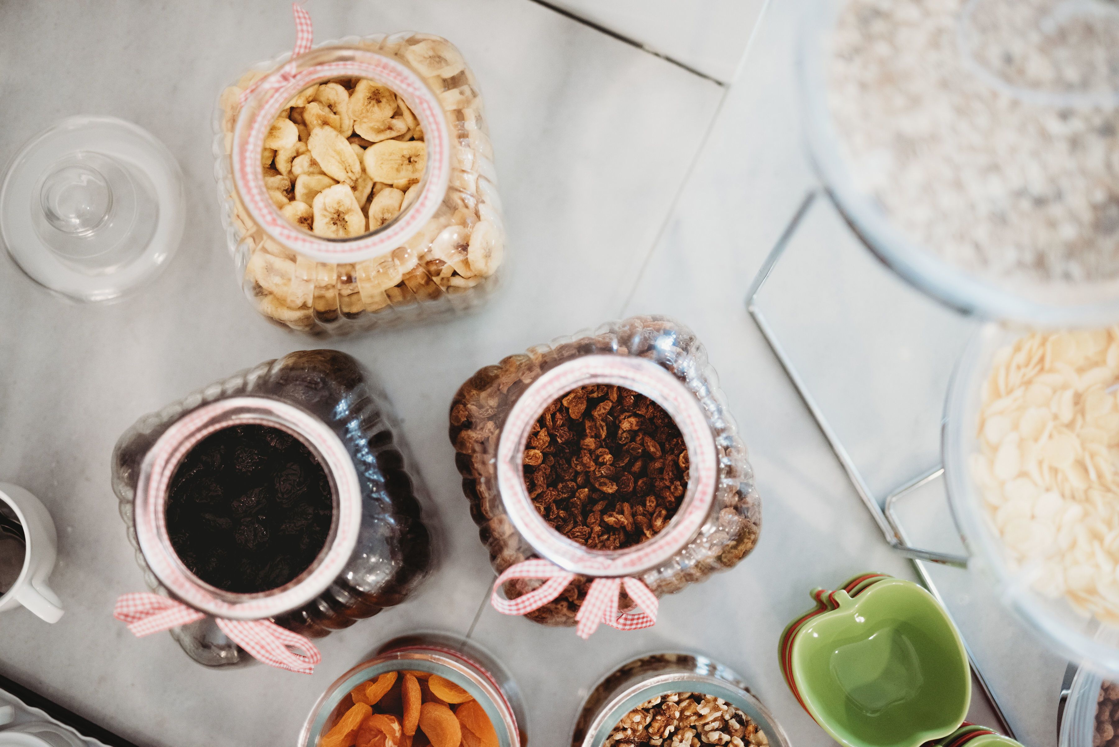 A top-down view of various food items in glass jars and bowls on a marble countertop.
