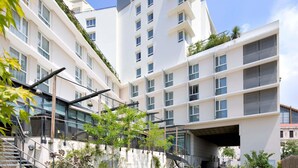 A modern multi-story building with balconies, a covered walkway, and a staircase leading to an upper level.
