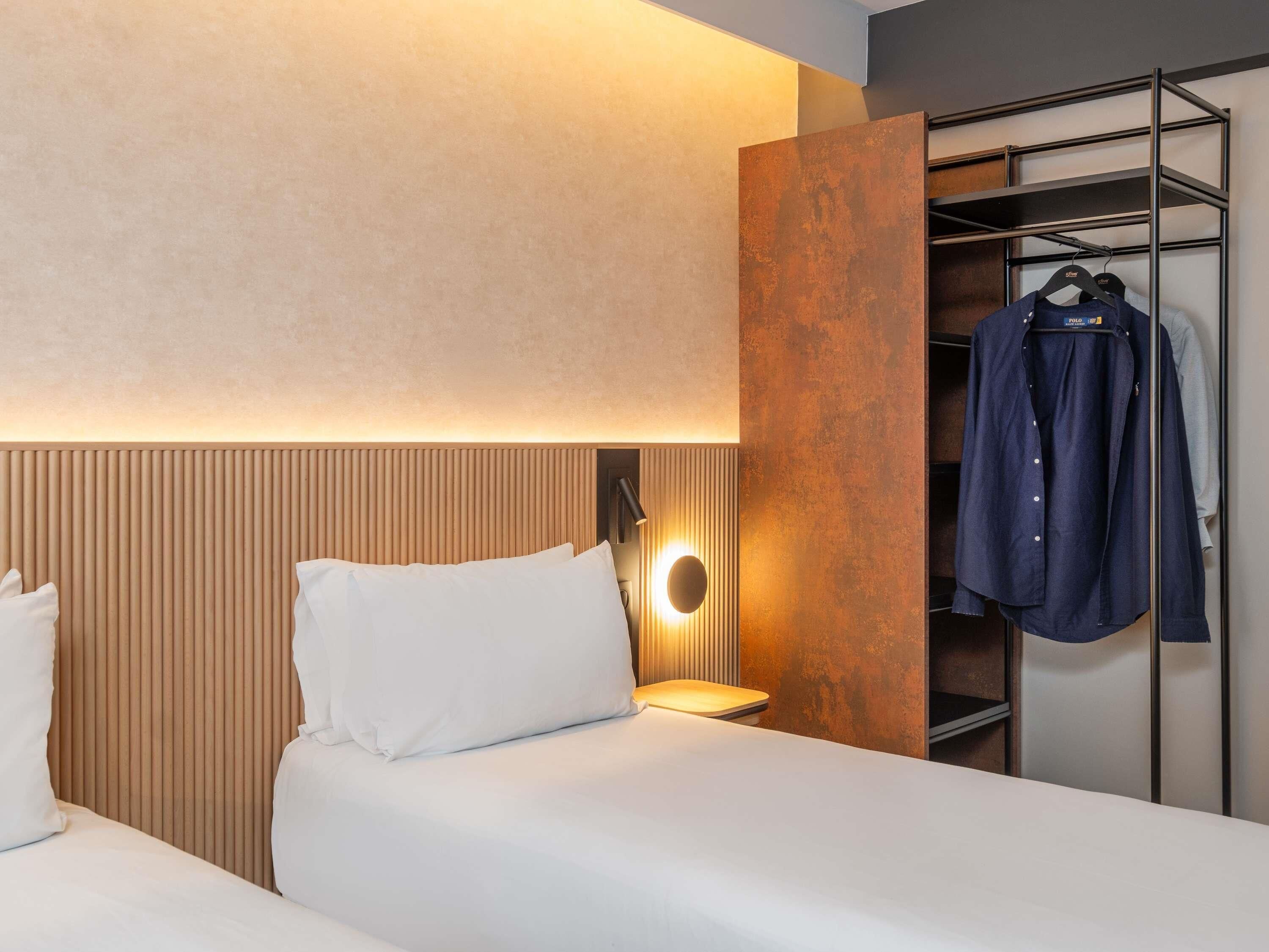 Une chambre d’hôtel avec deux lits, une armoire et un portant à vêtements.