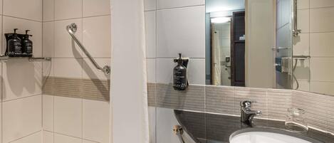 Un baño moderno con un lavamanos blanco, un cabezal de ducha de mano y un espejo.
