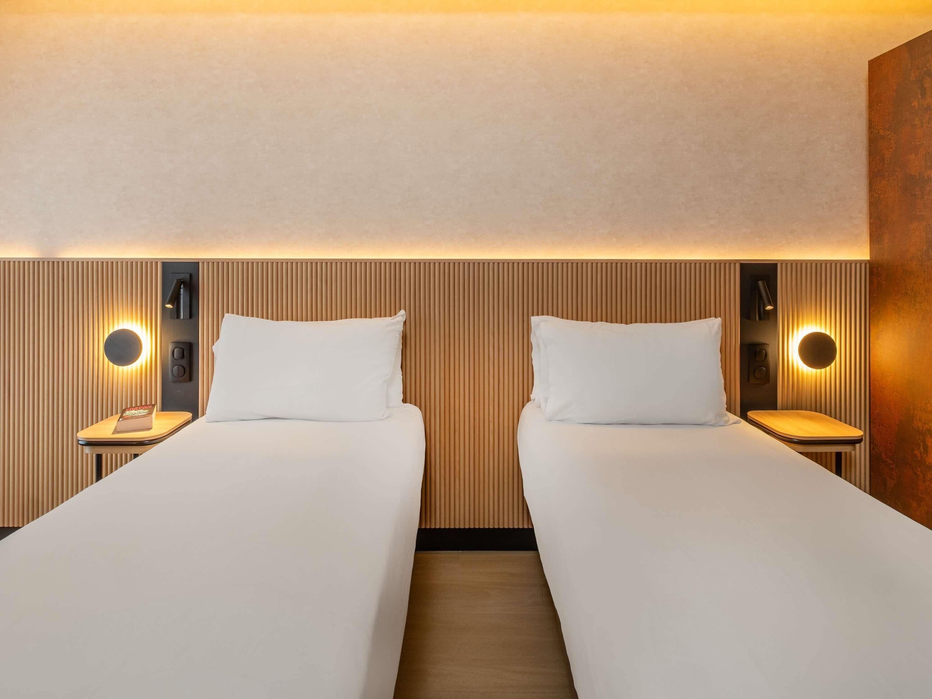 A hotel room with two beds, wooden paneling on the walls, and bedside lamps.