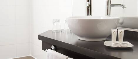 Un baño moderno con un lavabo blanco grande, un espejo y dos artículos de aseo en la encimera.