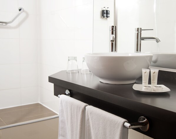 Un baño moderno con un lavabo blanco grande, un espejo y dos artículos de aseo en la encimera.