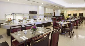 A modern dining area with a buffet setup, multiple tables, and chairs.