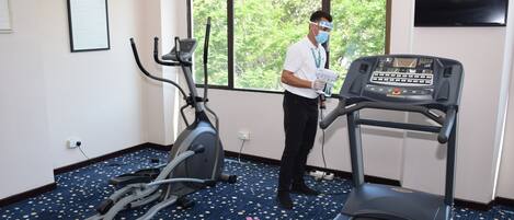 Habitación de hotel con equipo de ejercicio, una cinta de correr y una bicicleta estática.