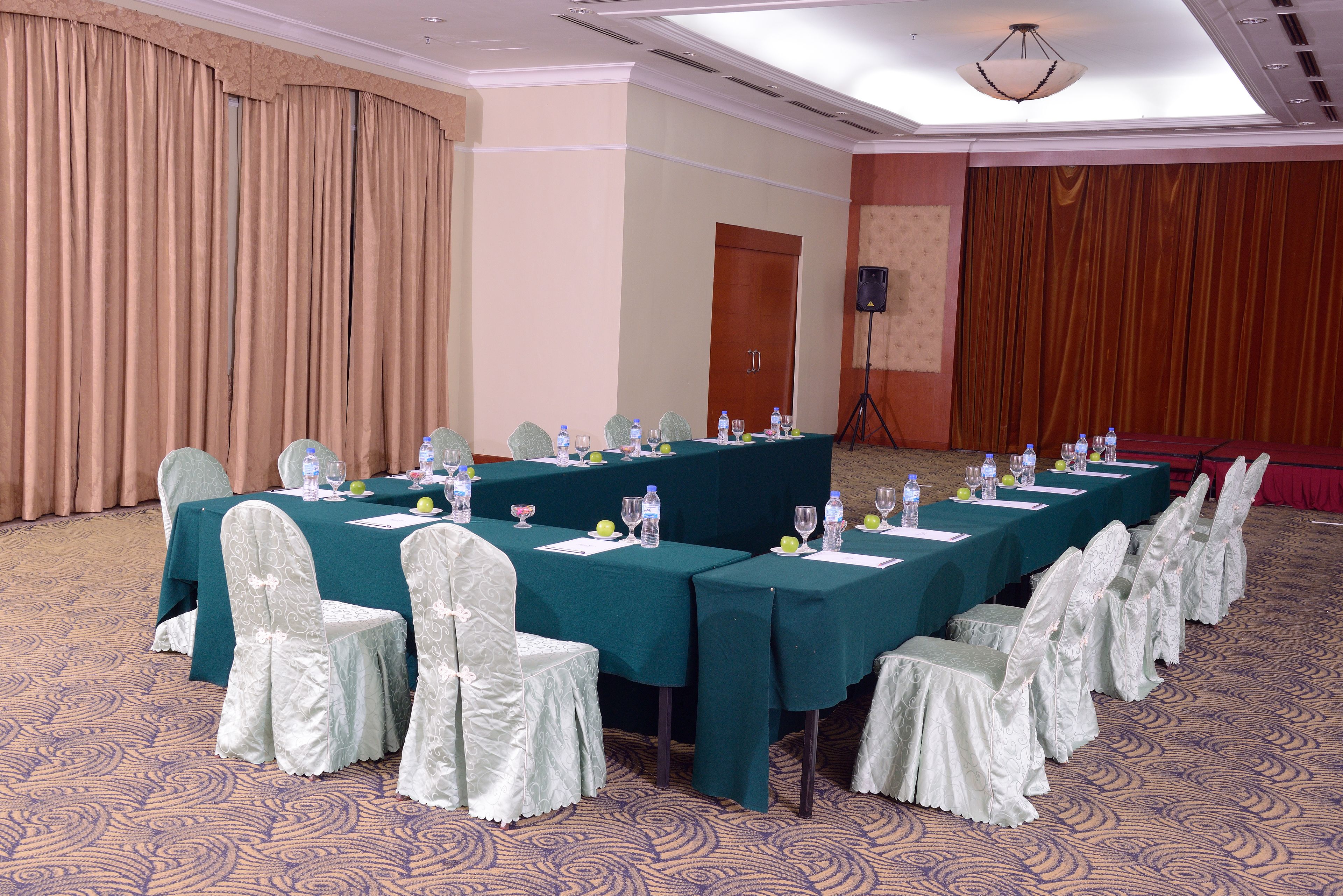 A conference room with multiple tables set for a meeting, each with chairs, water bottles, and documents.