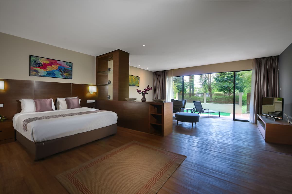 A modern hotel room with a large bed, a desk, and a view of the outdoors.