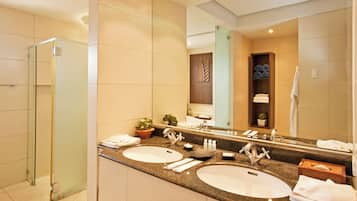 A modern bathroom with two sinks, a glass shower enclosure, and a large mirror.