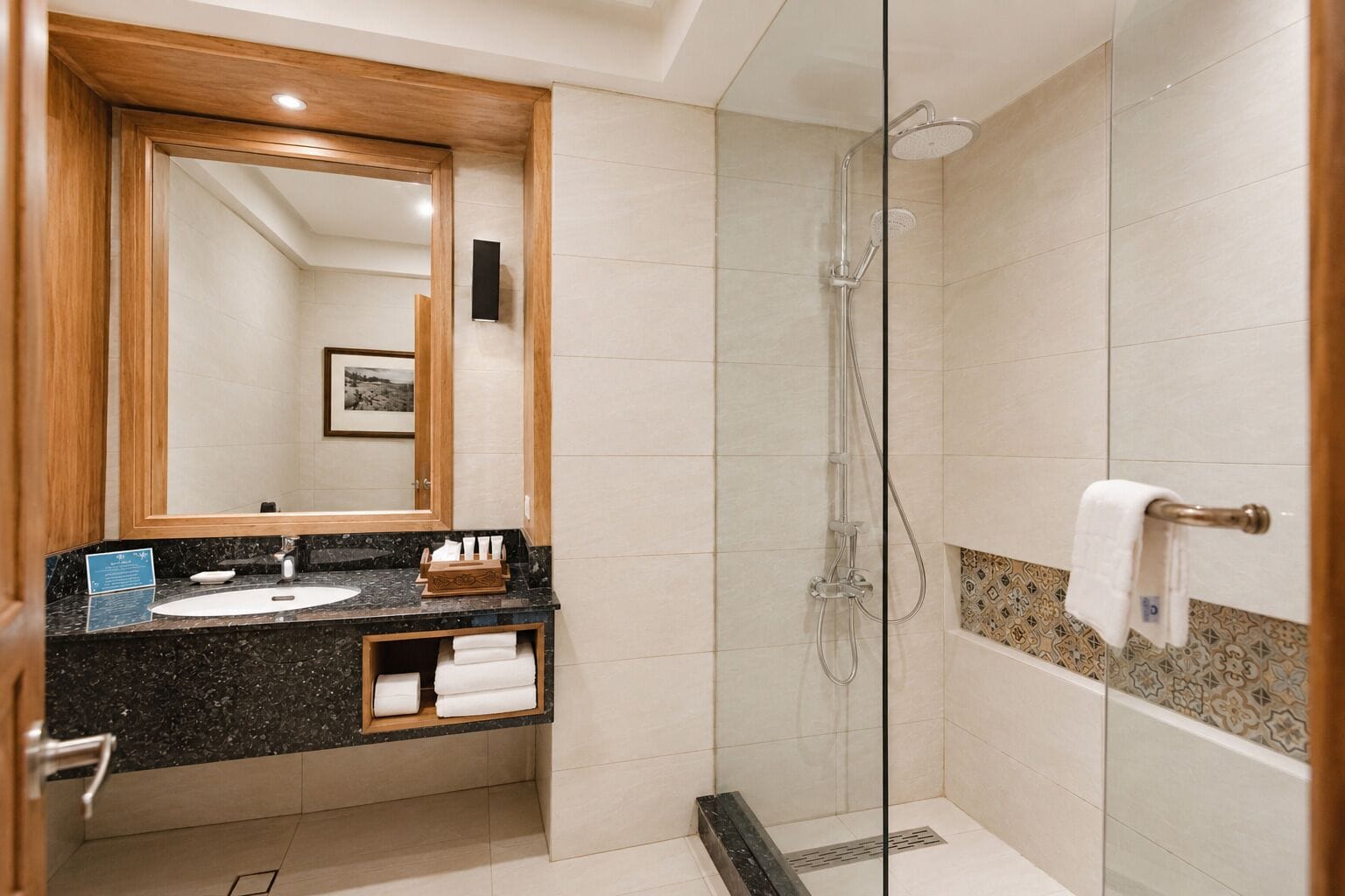 A modern bathroom with a glass-enclosed shower, a vanity with a sink, and a large mirror.