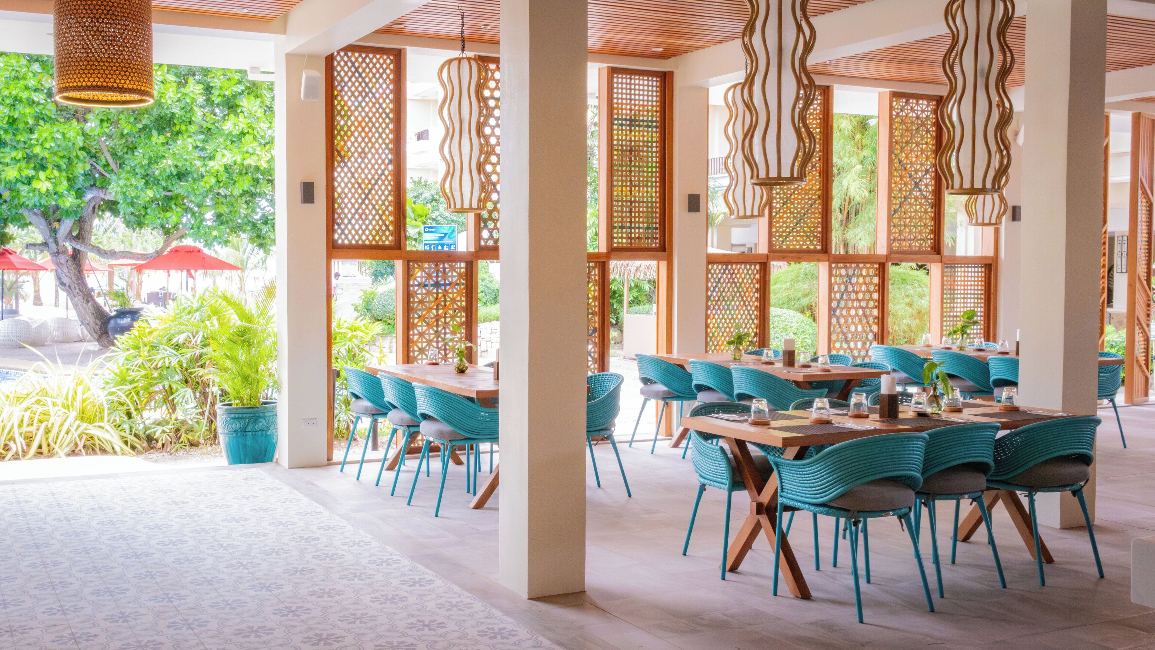 A restaurant with outdoor seating, wooden lattice partitions, and hanging pendant lights.