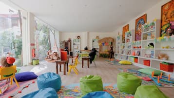 A spacious room with a large window, a play area with colorful bean bags, and a bookshelf filled with children's books and toys.