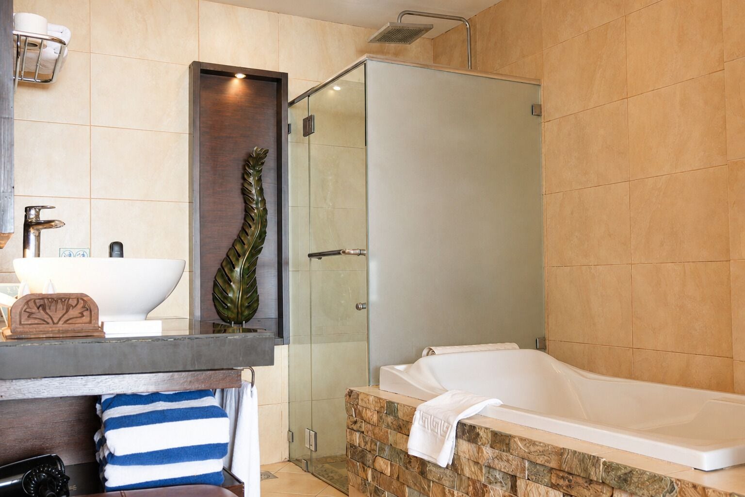 Un baño moderno con bañera, cabina de ducha de vidrio, lavamanos con encimera de madera y un perchero para toallas.