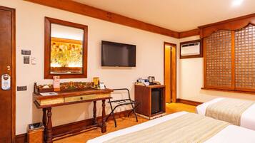 Habitación de hotel con un escritorio de madera, televisor, minibar, cama y una ventana de estilo asiático tradicional.