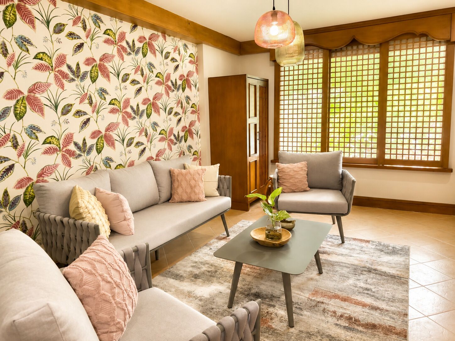Un salon comprenant un canapé, un fauteuil et une table basse, un papier peint à motifs et une porte en bois.