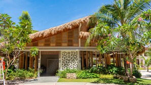 Un bâtiment doté d’un toit de chaume, de volets en bois et d’une entrée abritée.