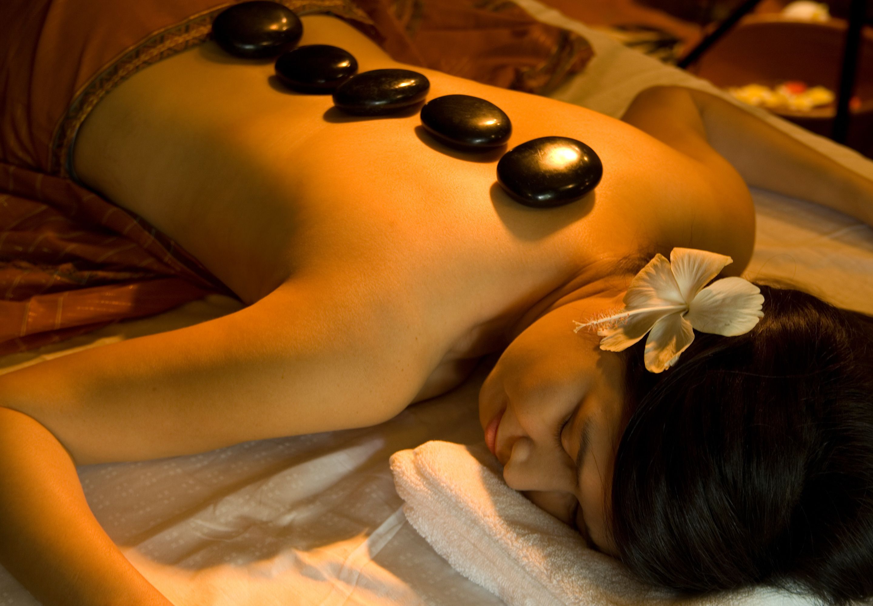 A person receiving a back massage with heated stones.
