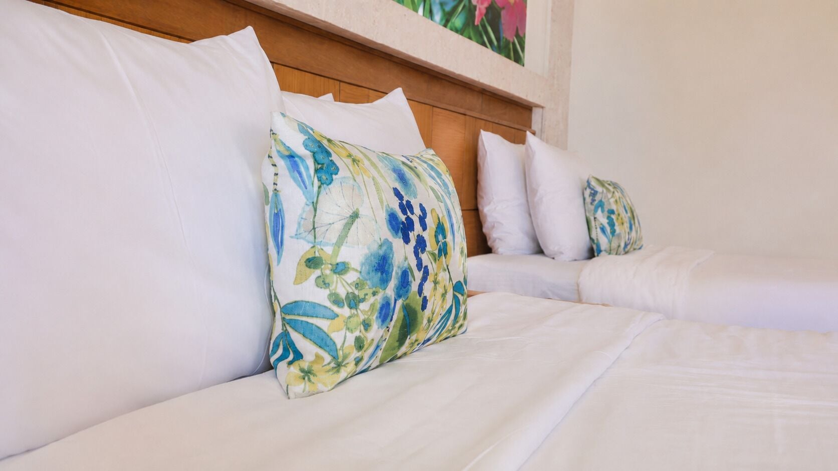 Ein Bett mit weißer Bettwäsche und einem blumigen Kopfkissen.